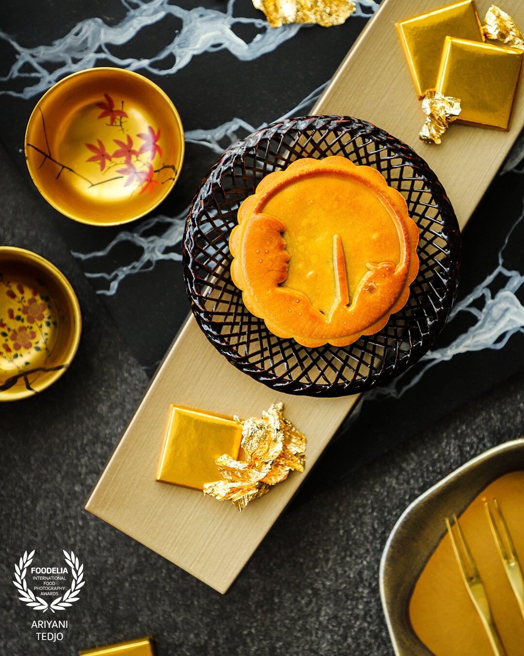 Matcha Lotus, Black Sesame and Valrhona Chocolate Mooncake. A special mooncake for Mid-Autumn Festival celebration this year, created by Chef Hideki Maeda of Nobu Singapore at Four Seasons Hotel Singapore. As this particular delicacy is incorporating Japanese culture into a traditional Chinese, the props used are a reflection of both cultures. The golden color chosen for this scene was inspired by the luxurious lacquered gift box that came with the mooncakes.
