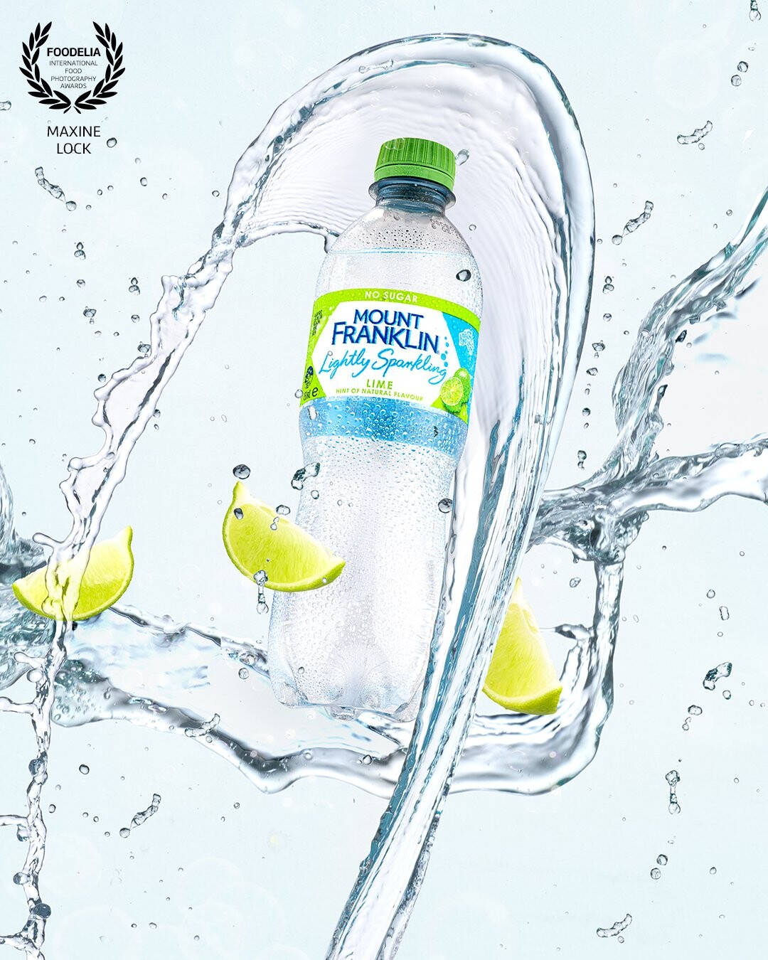 Lime flavoured sparkling water surrounded by splashes of water and lime wedges. Water droplets added to the bottle, and bubbles added to the background, to further emphasise the cold sparkling bottle of water.