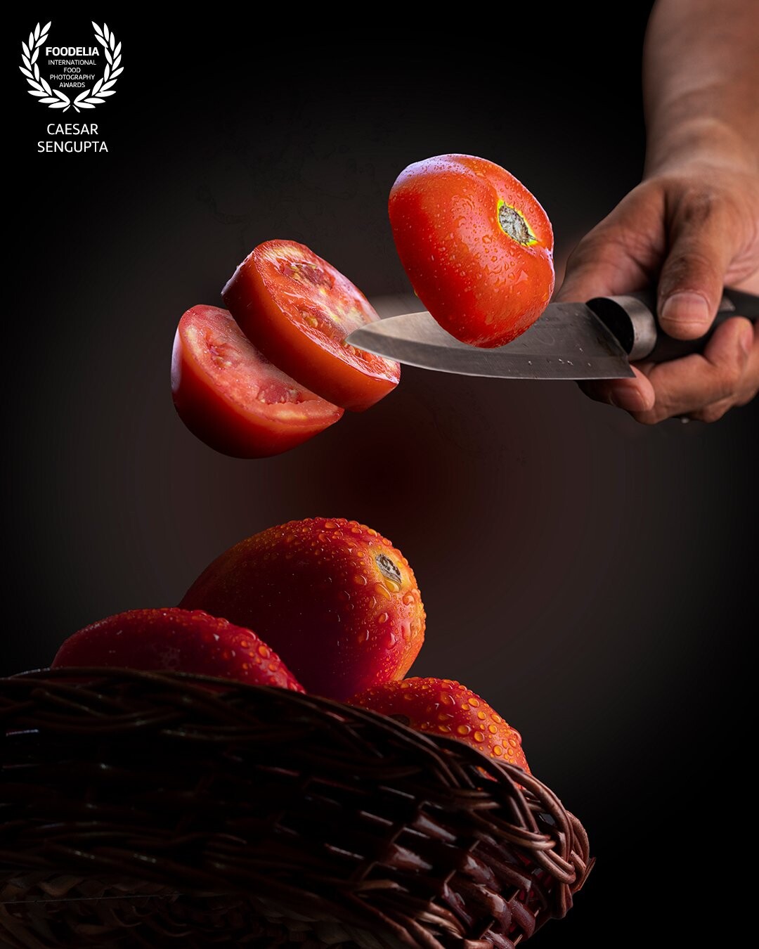 A dark and moody levitation image with predominance of red as the strongest colour. The perspective is from below to add a dramatic effect. The cut tomatoes are shot separately. The water droplets add freshness to the vegetables. A slight motion blur applied to the knife bringing in a sense of motion.