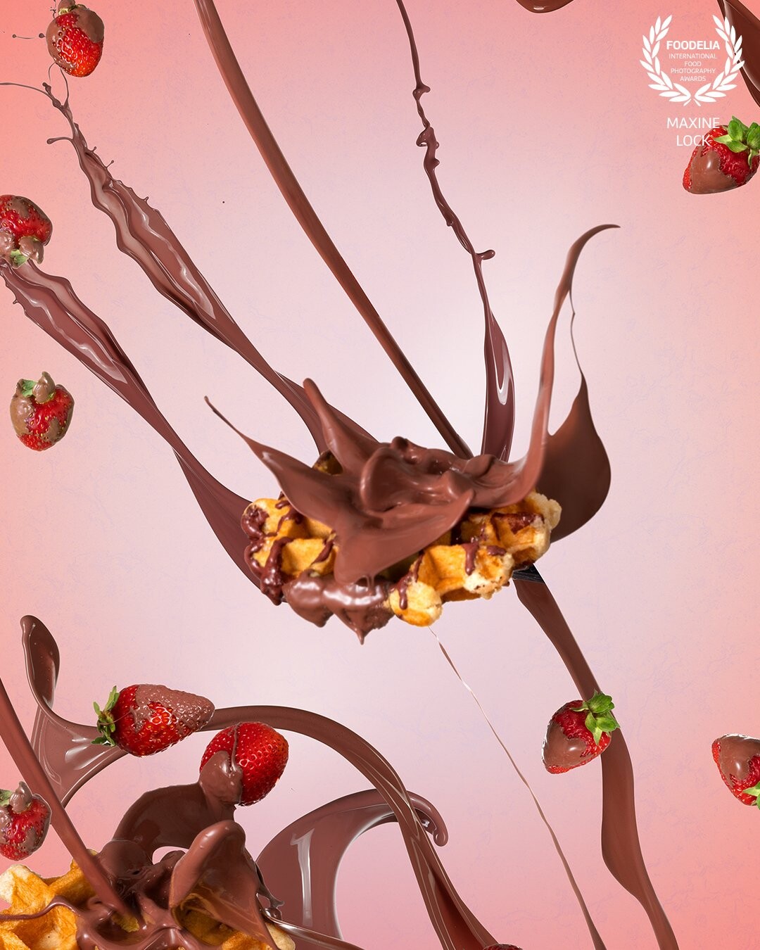 Chocolate splashes colliding with multiple waffles in the image, with strawberries being thrown around along with a pink background to compliment.