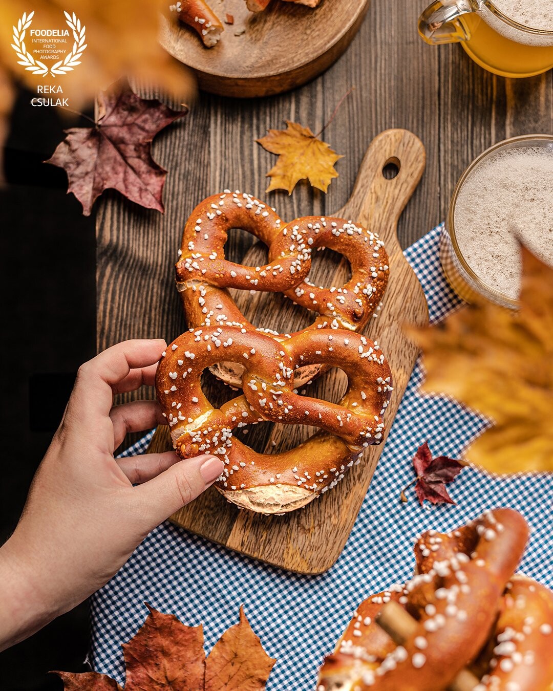 Seasonal photoshoot with Octoberfest vibes, layering for 3-dimensionality using colourful leaves and typical items of a true feast for pretzels and beer.