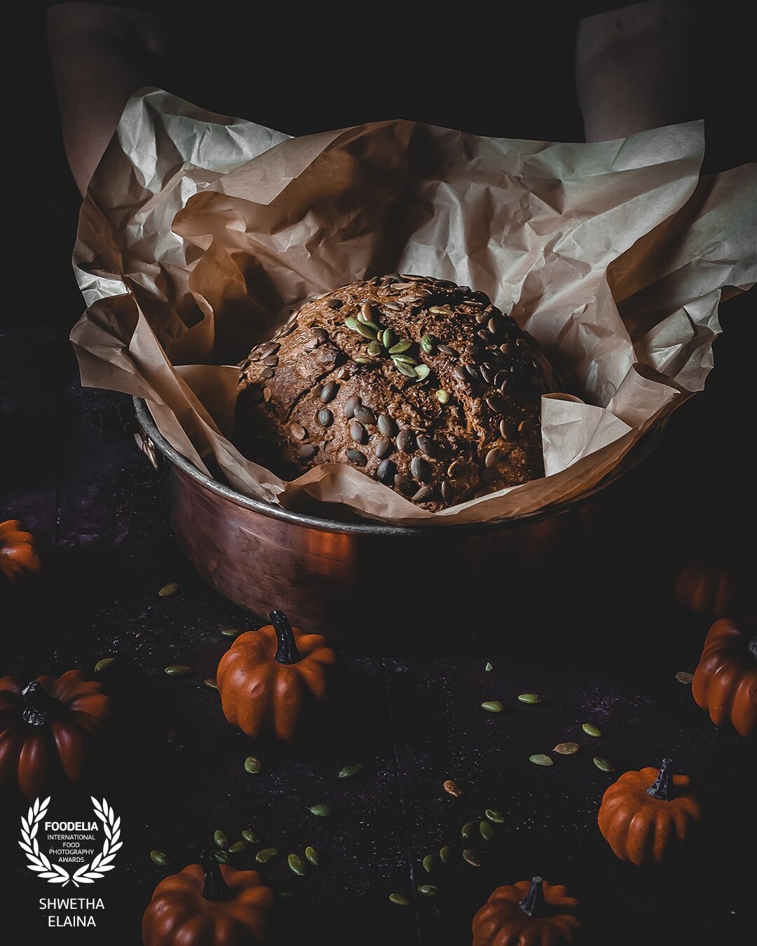 A homemade GF pumpkin boule bread topped with pumpkin seeds. An attempt to keep the scene minimalistic and highlight the colors and textures on this bread.