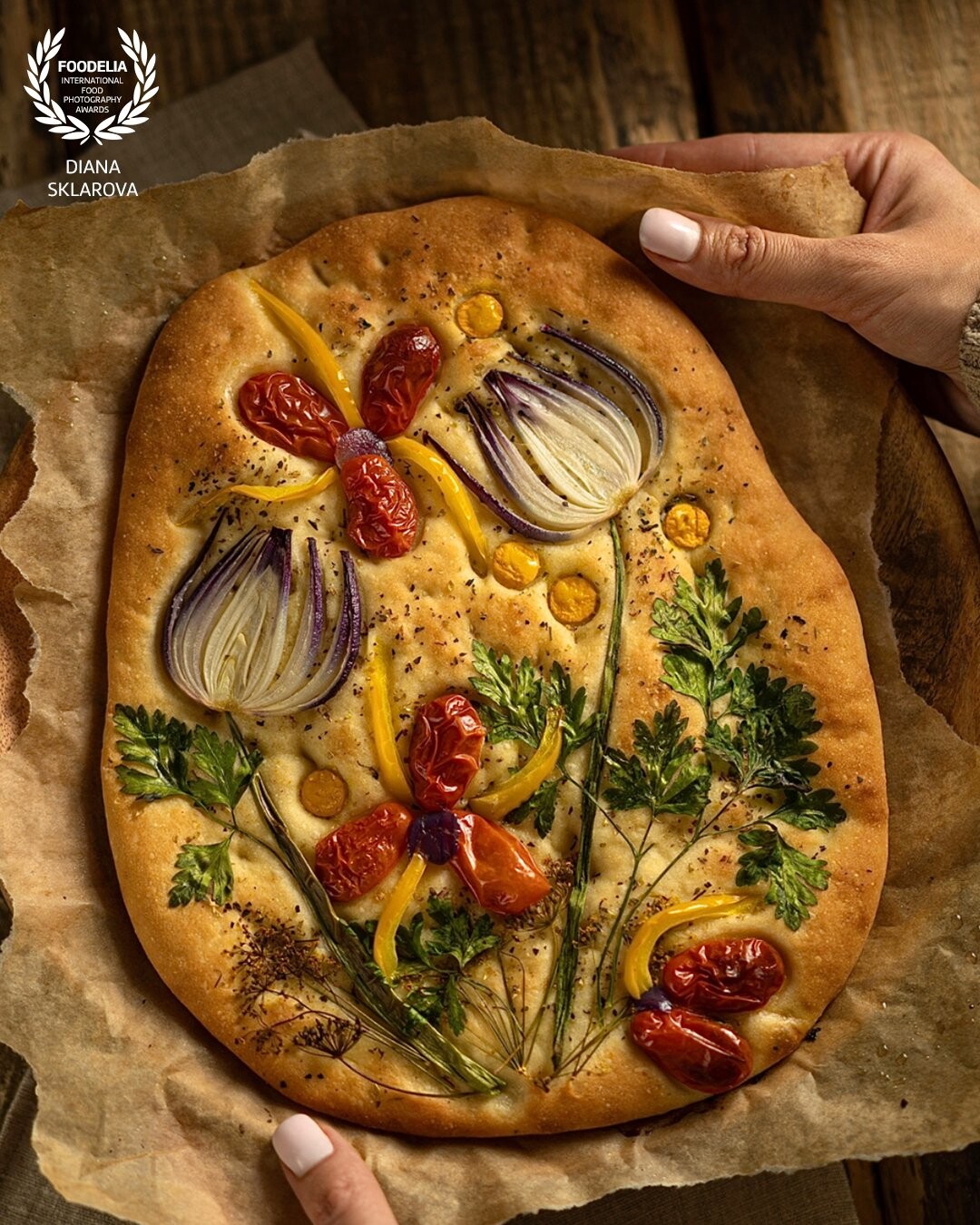 Garden art focaccia bread with vegetables, greens, herbs - beautiful flower composition on homemade freshly baked bread on wooden background.