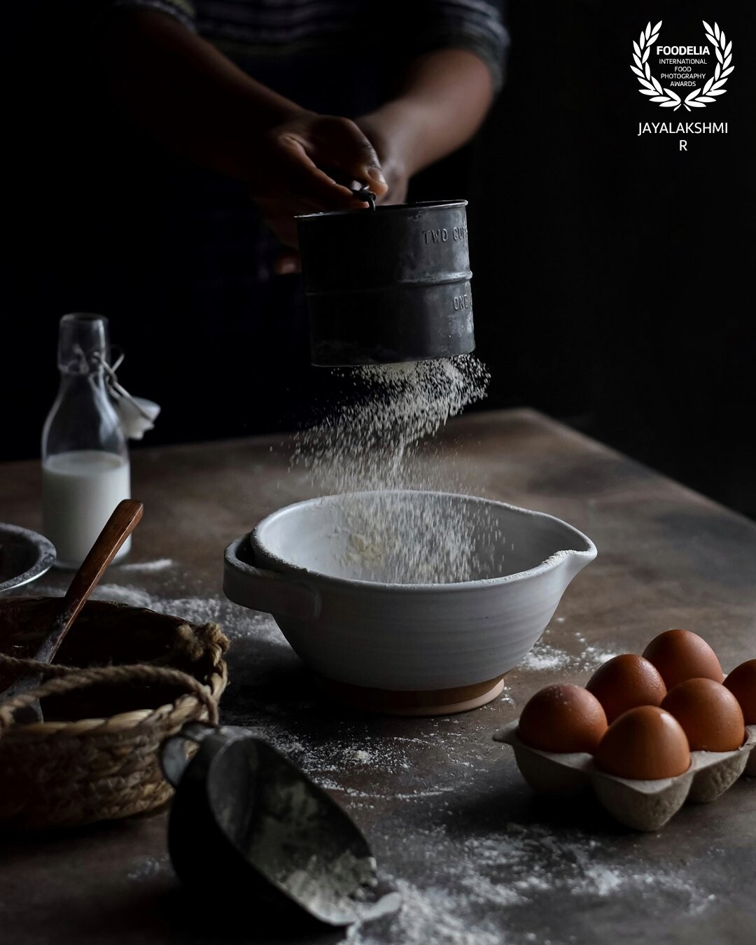 A process shot from my long pending list . Wanted to capture a process shot , involving a flour drizzle action . Set up a regular baking scene . Shot in natural light and brought out a moody light set up.