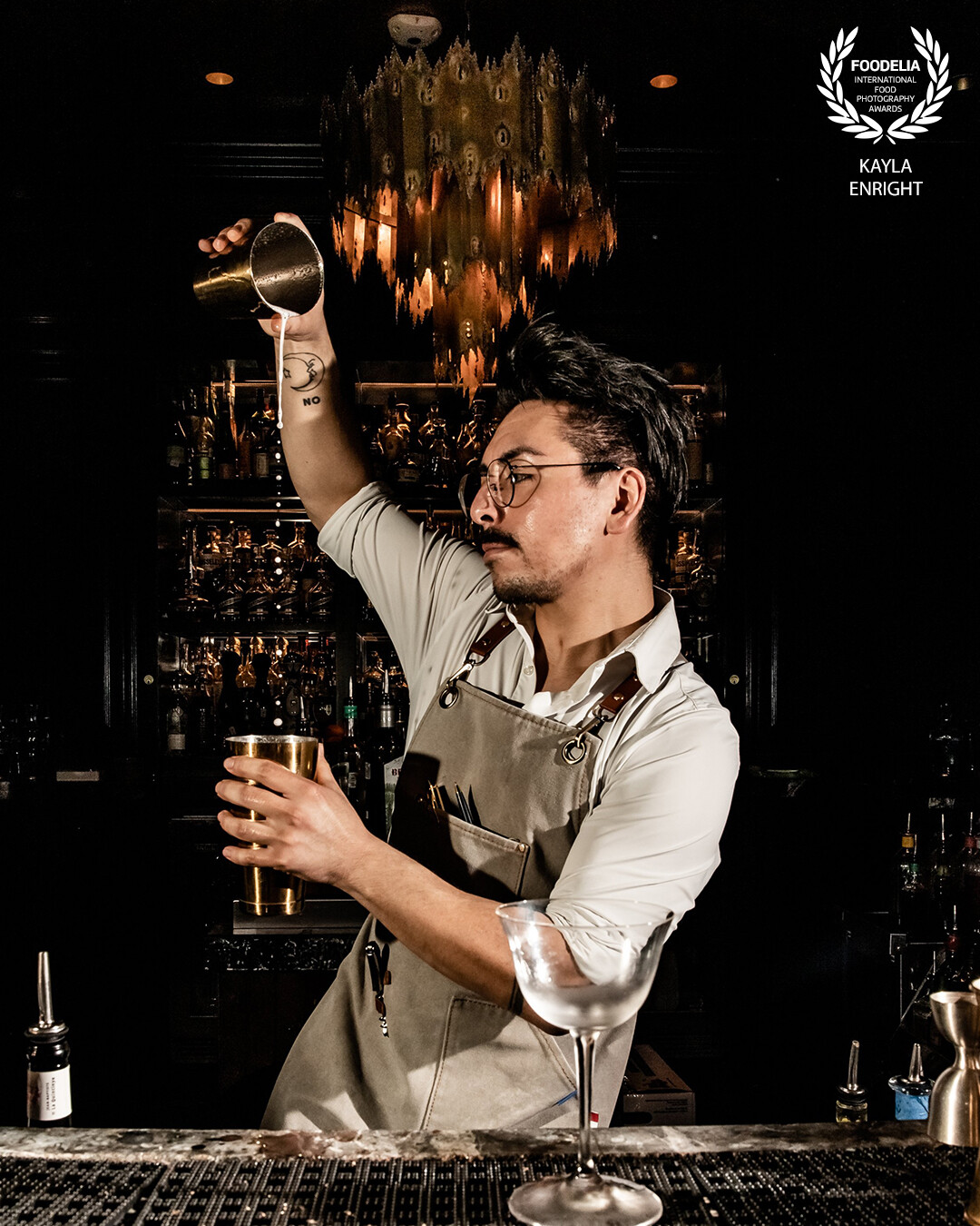 A mixologist continuing to perfect his craft in the darkness of a classic upscale bar.
