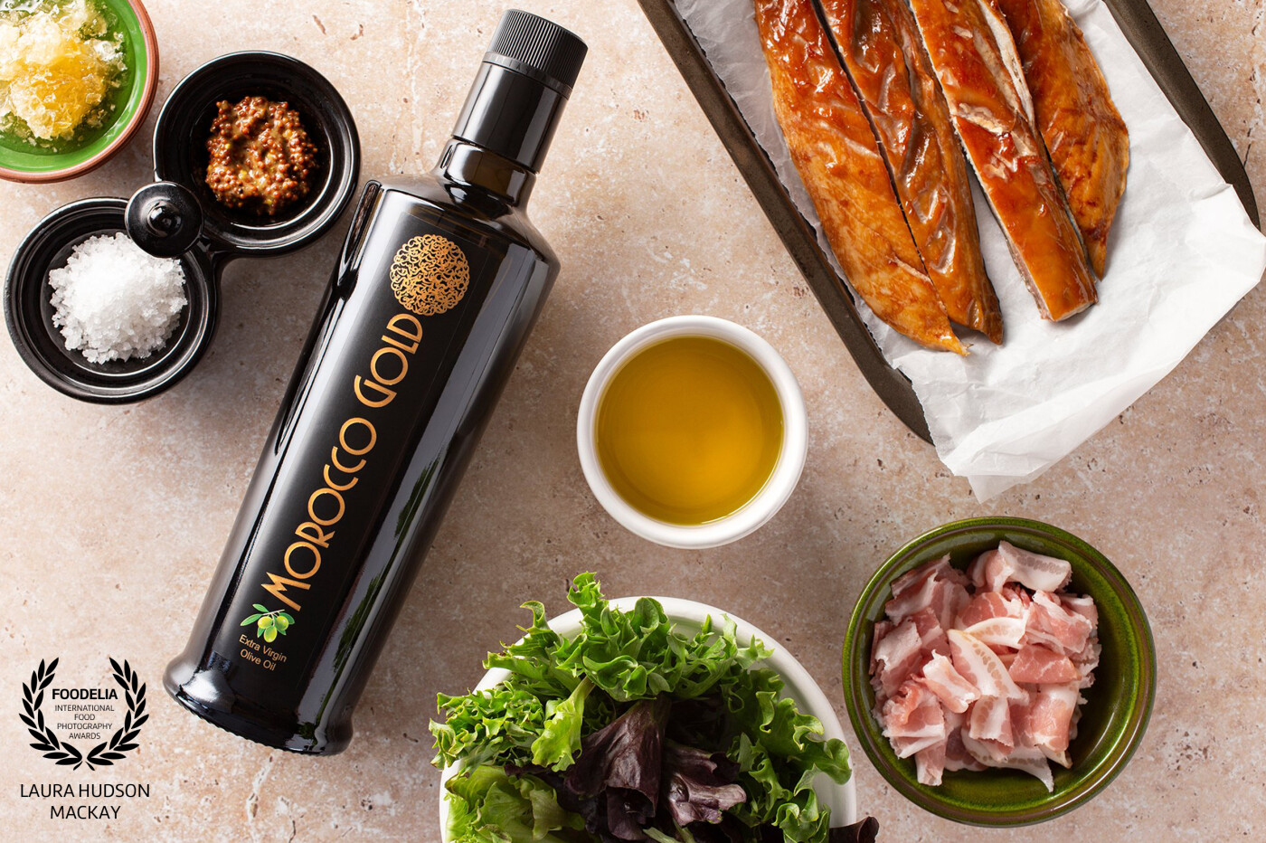 A bright and airy photoshoot of ingredients for a delicious lunch. Mackerel, smoked bacon, salad leaves, mustard, honey and sea salt, drizzled with award winning luxury Extra Virgin Olive Oil by Morocco Gold.