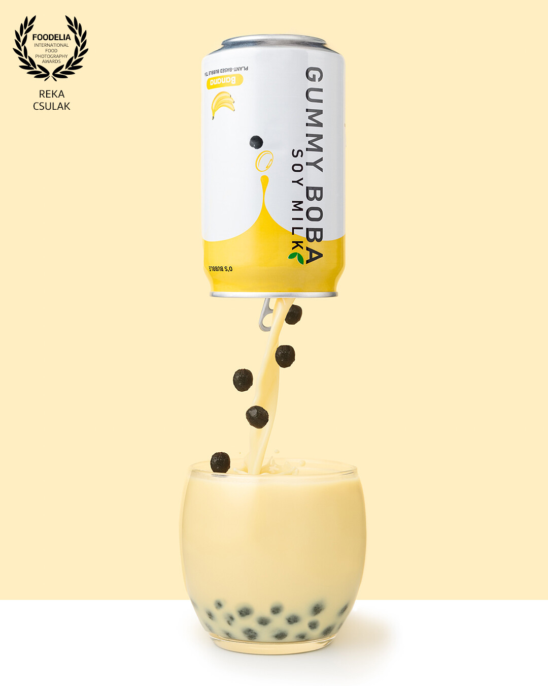 Banana boba drink product photo with monochromatic styling, unusual perspective and some action incorporated.