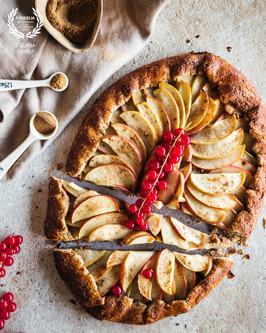 Homemake apple galette decorated with fresh red currants . Shot with Canon EOS R6 and natural light in my home studio.