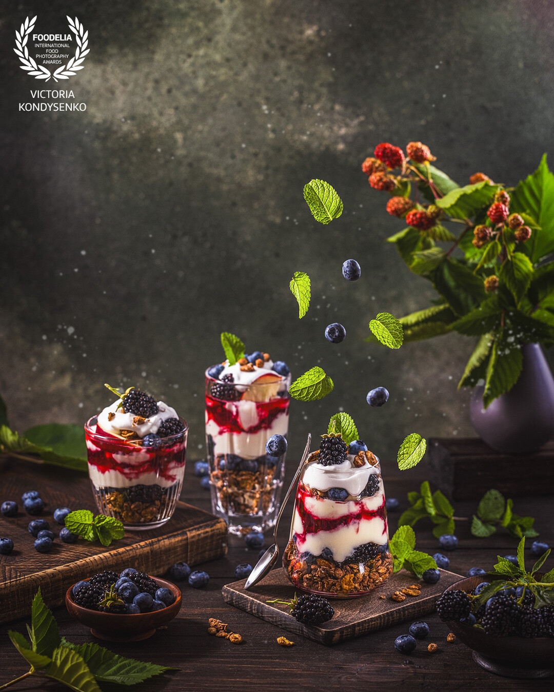 Homemade granola with greek yogurt, berries jam and fresh blackberries and blueberries in glasses. Advertising photo shoot of the local Ukrainian family cafe