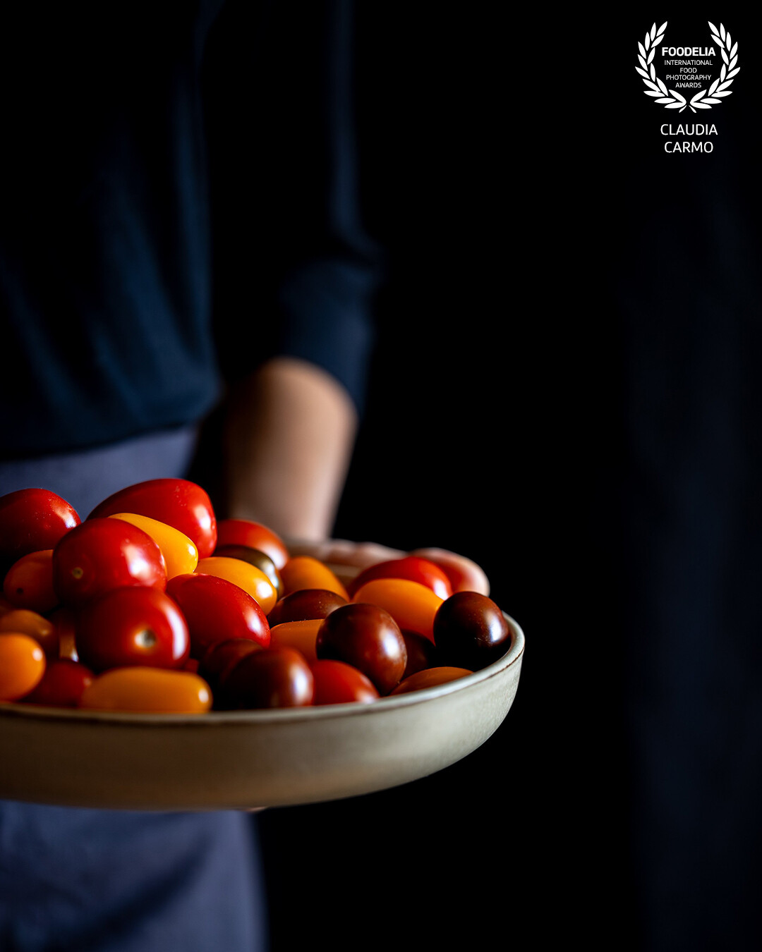 Fresh cherry tomatoes offered on a plate, photographed in natural light with a Canon 6D Mark II and a Canon 100mm Macro Lens.