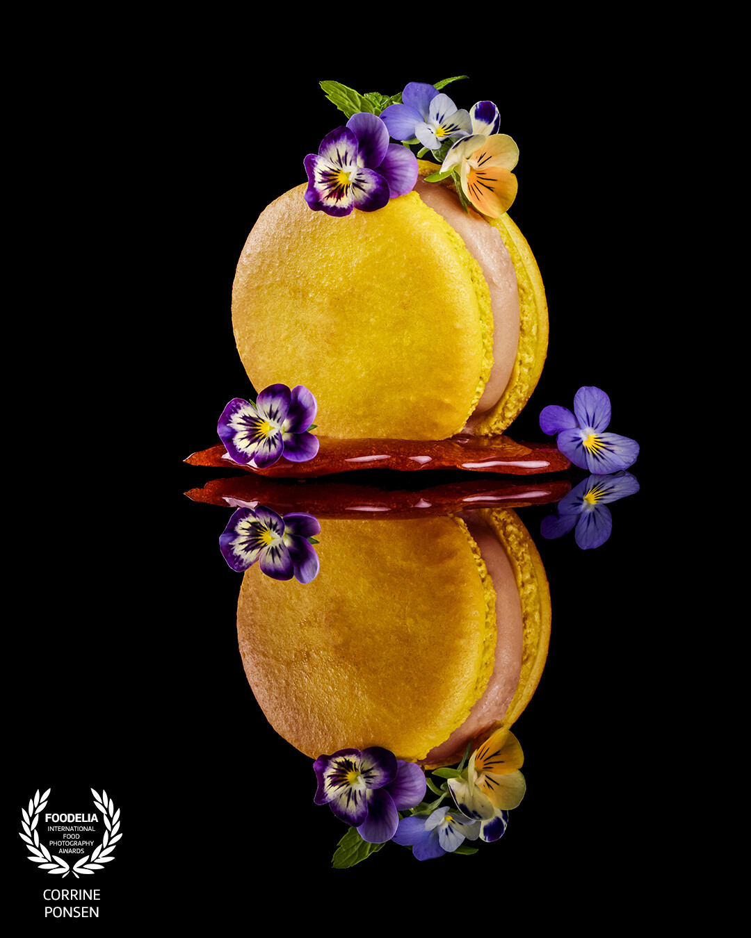 Photographing a macaron is not easy to do. I want something else, so I try to do that. In this picture a placed the macaron on a caramel stand and decorated it with some eatable flowers. I give the macaron some backlight and the mainlight came from the right. The reflection makes it more special and is my signature.