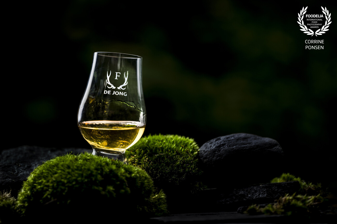 For several years I am making pictures for a client, who sell whiskey and wine glasses. This time the location is my own garden. I love to shoot in our beautiful green lush jungle garden. With just one flash as a backlight I take this picture. The rocks and the moss are placed on a wooden table, the wiskey is real, not a fake blend ad you can see how it stich to the glass. I used my 200 mm lens and shoot it on aperture 2.8 for a lovely bokeh background.