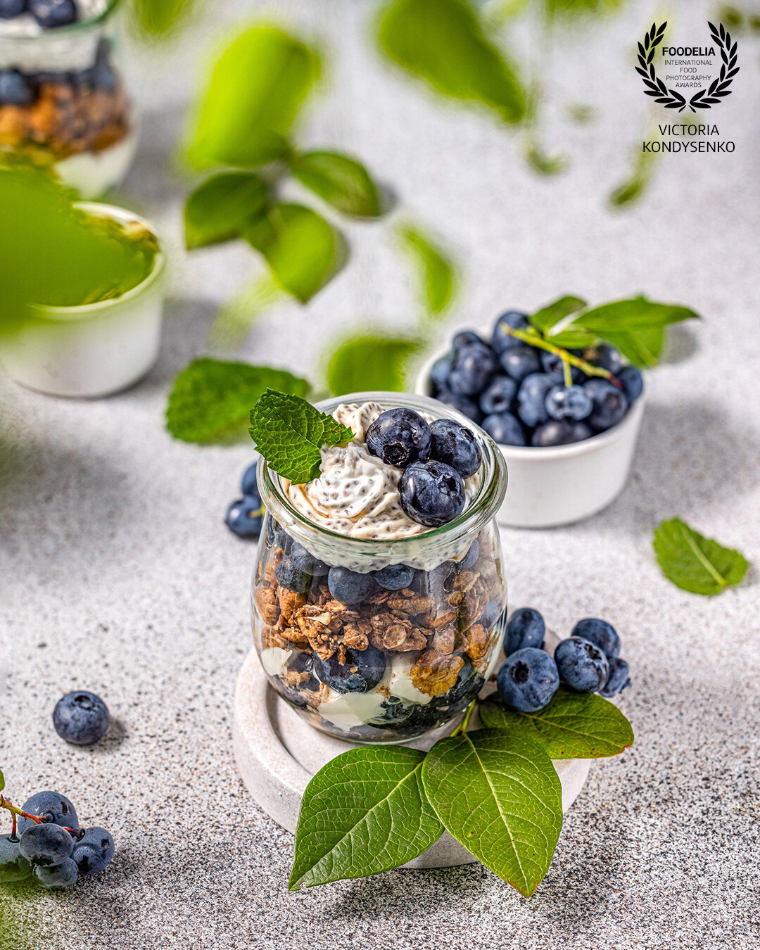 Homemade granola with Greek yogurt, maple syrup and fresh blackberries and blueberries in glasses. Promotional photo shoot of the local Ukrainian family cafe.
