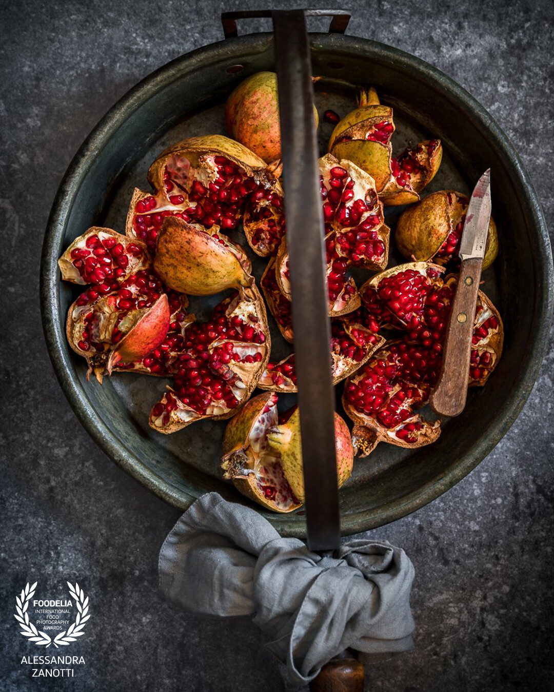 Here, using a single light source, this captivating photograph captures the evocative essence of pomegranates in a dark and moody style. The intense details, illuminated by the focused light, add a touch of drama to the composition, transforming the pomegranates into the compelling focal point of the image.