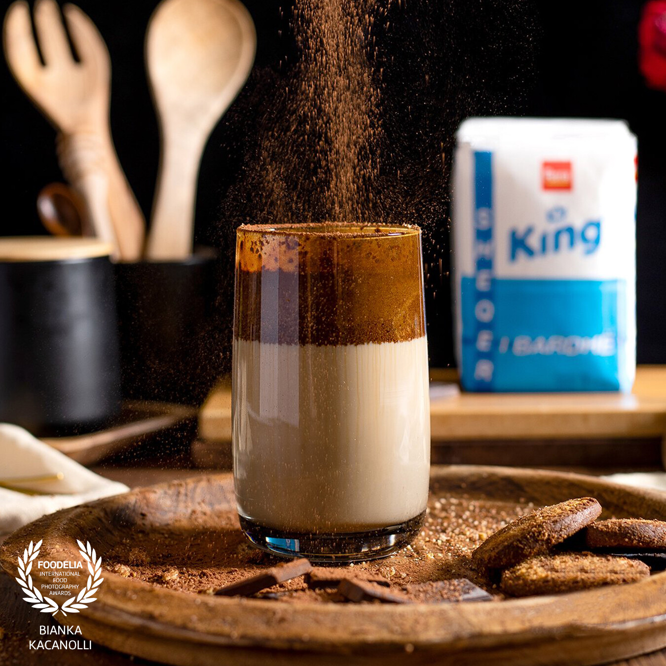 Coffee with chocolate and cocoa powder on top. The concept of the photo is based on one of the ingredients such as sugar, placed in the background, which is used for sweetening but not as the main focus. This is a photo taken in the DC Media Group studio for one of the most famous sugar companies in Albania, Ferra & Co.