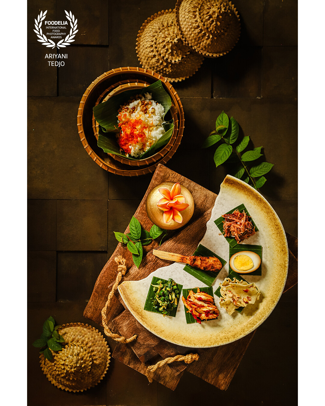 A popular Balinese meal called Nasi Campur Bali. Usually the rice and the side dishes are served all together on a single plate; the one here separate the rice and the side dishes. Two Balinese frangipani blossoms are used as decoration.