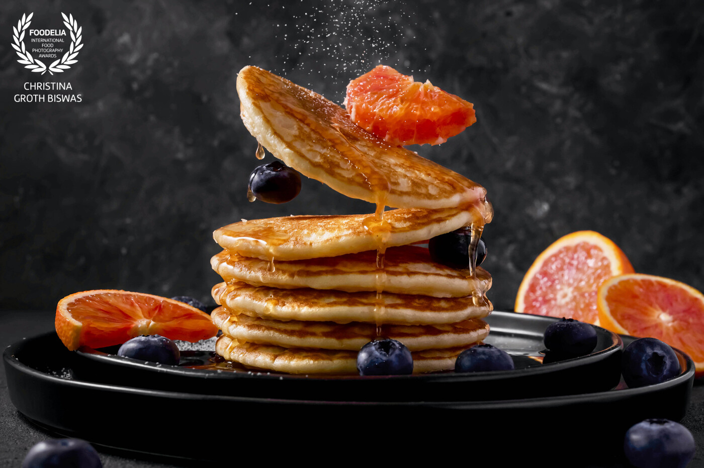 Levitation image of a stack of buttermilk pancakes with blood oranges and blueberries.