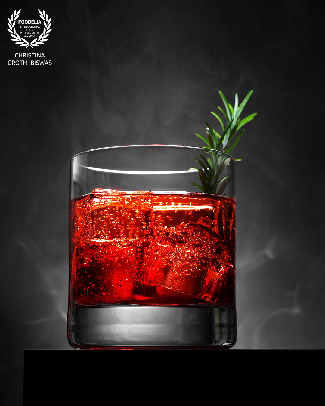 Campari soda, garnished with fresh rosemary. <br />
<br />
I placed the main light behind the drink to bring out the intense red colour of the Campari and used a reflector pointing to the rosemary. The smoke in the back is real.