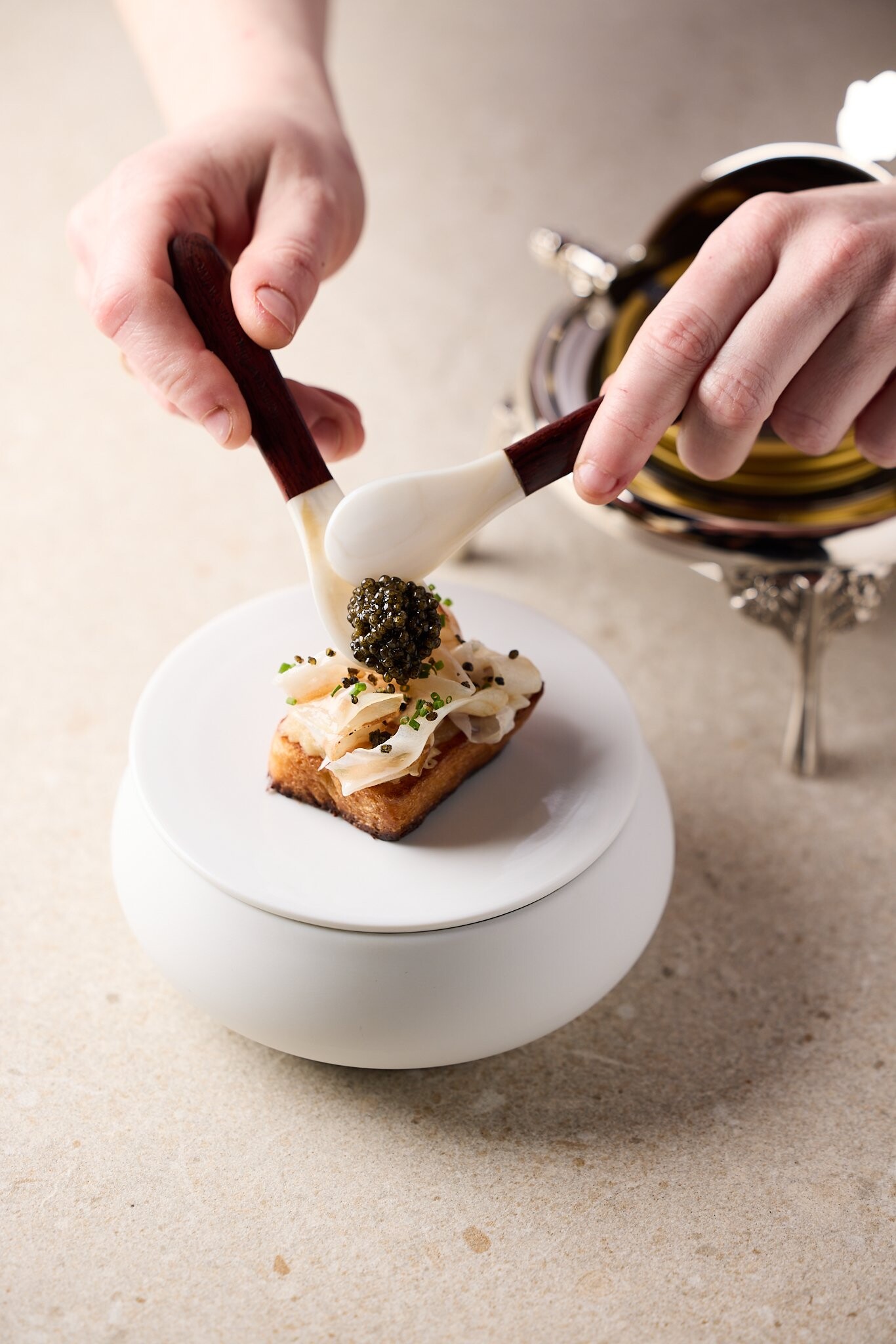 A lukewarm brioche with compote of Cévennes onion, guanciale and Imperial Heritage caviar. Shot at r...