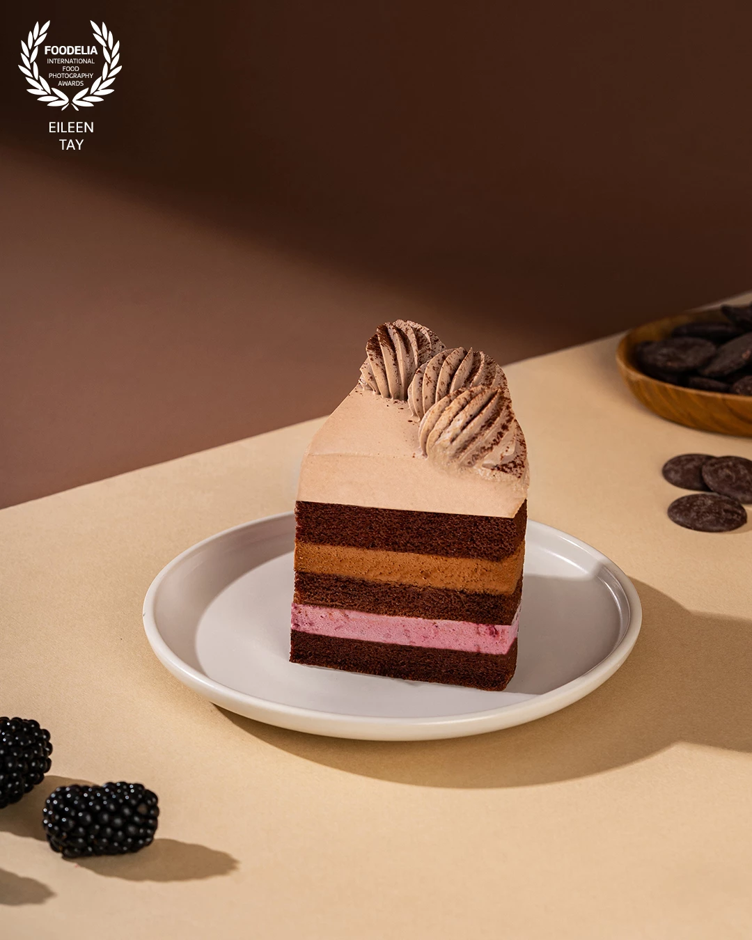 The hard light forms bold shadows and highlights the cake’s textures, especially the velvety frosting and layered interior, making the dessert appear more dimensional and luxurious.