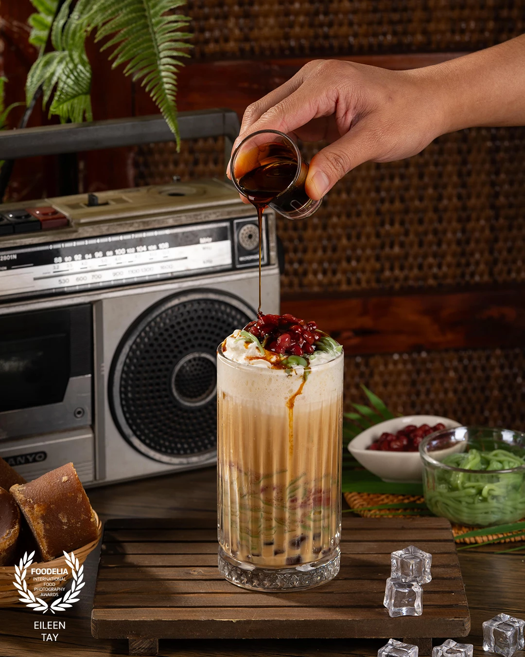 The concept evokes the feeling of a traditional Malaysian style enhanced by the presence of classic props like a vintage radio and wooden elements.