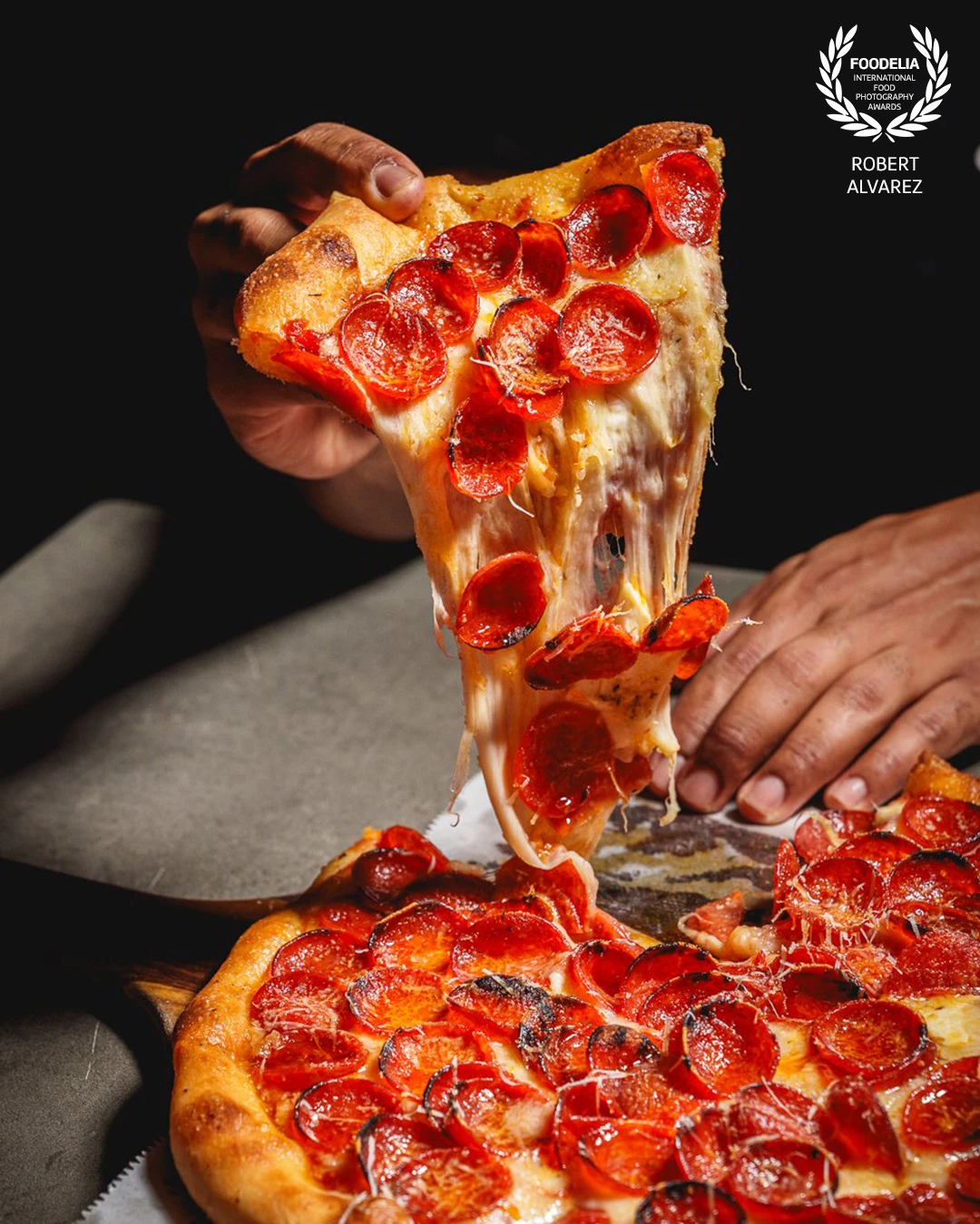 This shot captures the perfect pizza moment at Bar Museo in Coamo, Puerto Rico — a hot slice of pepperoni pizza being lifted, with gooey melted cheese stretching in irresistible strands. The dramatic lighting highlights the textures: the golden blistered crust, the glistening pepperoni, and the pull of the cheese, making the image feel almost tangible. The composition places the viewer right at the table, evoking the sensory experience of grabbing that first slice.<br />
<br />
It’s a photo that celebrates not just food, but the shared joy of pizza, captured with intensity and precision.
