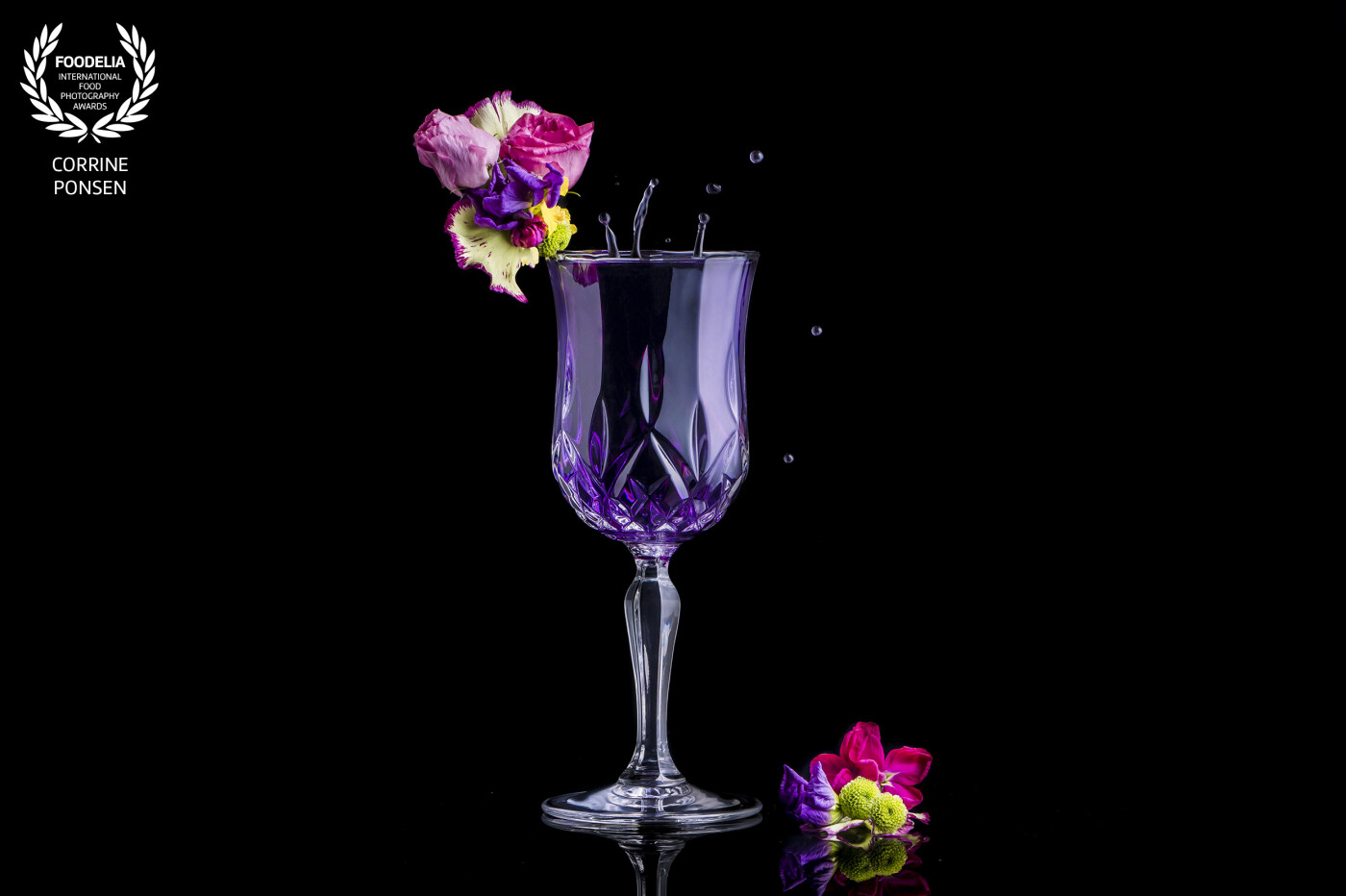 I take this picture of a crystal glass for a company who sells the most beautiful wine and whiskeyglasses.<br />
I shot this wineglas with a purple drink because the glas is also used for cocktails. I styled the flowers and with just a little splash there is some movement in the picture.