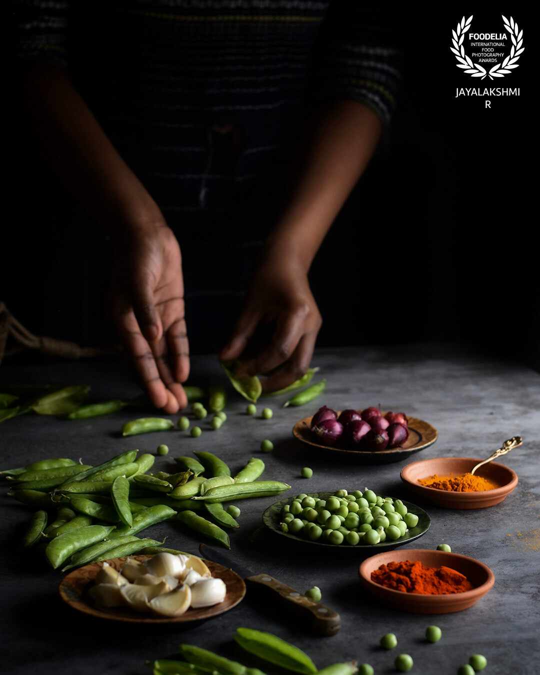 A typical kitchen scene .  Shelling out fresh green peas , included our regular spices for a bit of contrast in the frame .