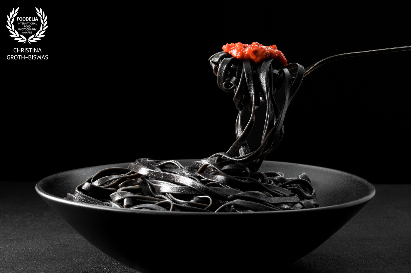Squid ink linguine with hot chilli pesto.<br />
A black subject on a black background is always a bit tricky to capture, hence I used artificial light which gives better control. I also added a strong contrasting colour which not only works on the picture but also added a lot of flavour to the final dish.
