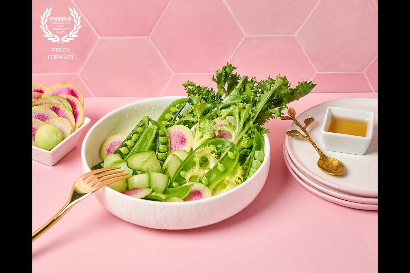 This salad celebrates Spring with a bed of mixed greens that provide a variety of textures and flavors. <br />
The vibrant pink backdrops emphasizes the colors and textures of the salad, making it look even more enticing.