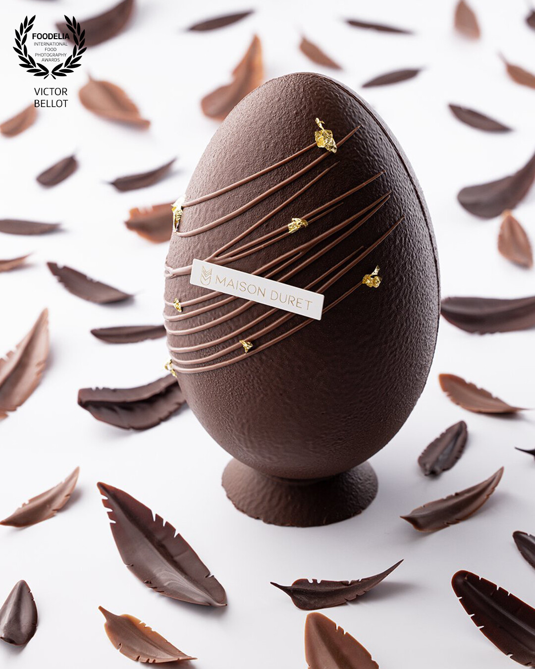 The dark chocolate Easter egg from Maison Duret staged with dark chocolate and dulcey nibs.